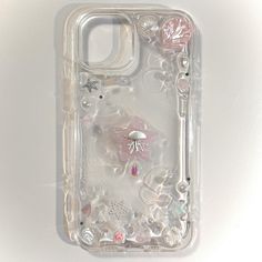 a clear case with pink flowers and seashells on the bottom is shown in close up