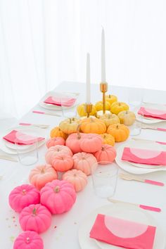 the table is set with pink and yellow pumpkins, candles, and napkins