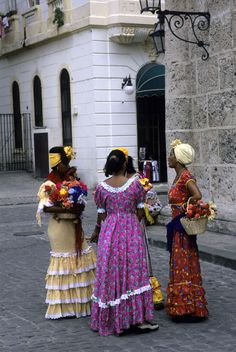 three women in colorful dresses are standing on the street and talking to eachother