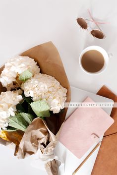 a bouquet of flowers sitting on top of a table next to a cup of coffee