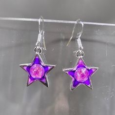 One of a kind hand painted (gradient purple blend) and resin (creates a glass like finish) dangling star earrings.  Embellished with embedded Austrian crystal (electric violet) star charms are silver plated pewter. Hung on sterling silver .925 stamped French ear wires.  Approximate length 1.25". Stars are for dreamers, doers and believers. The magic of possibilities is among the stars, in the heavens of our ideas and the wishes we keep or share with the world. Photos taken in studio light.  Free U.S. shipping on orders over $35. International shipping available. Same item as shown, contact me for free sizing adjustments. Shipped in a sealed and protected plastic bag. Free customer consultation offered to create a client profile I keep on hand with measurements and preferences for future or Nickel-free Silver Resin Earrings, Star-shaped Resin Jewelry For Gifts, Star Shaped Resin Jewelry Gift, Silver Resin Earrings As A Gift, Silver Resin Earrings For Gift, Handmade Purple Resin Jewelry, Purple Round Resin Jewelry, Silver Jewelry With Glossy Finish For Gift, Nickel-free Purple Enamel Jewelry