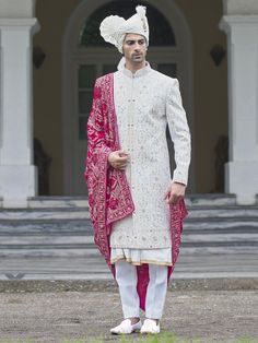 a man wearing a white and pink outfit standing in front of a building with steps