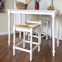 a white table with two stools and a basket full of bread on top of it