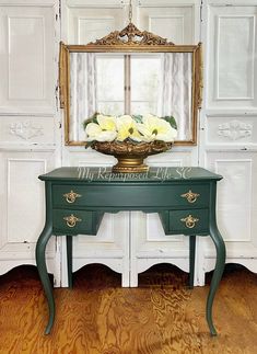 a green table with flowers on it in front of a mirror and white wallpaper