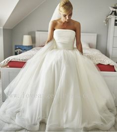 a woman in a wedding dress sitting on a bed