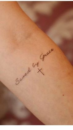 a woman's arm with the words saved by grace tattooed on her left arm