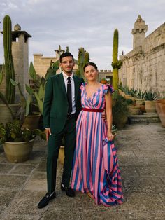 a man and woman standing next to each other in front of cacti plants