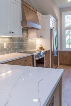 a kitchen with white marble counter tops and wooden cabinets, along with stainless steel appliances