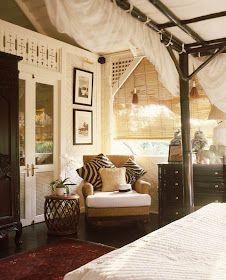 a bed sitting under a canopy next to a white couch and chair in a bedroom