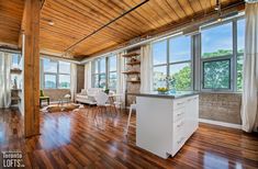 an empty kitchen and living room with wood flooring in a loft type apartment building