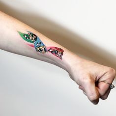 a person's arm with three cartoon characters on it and one is holding the other hand