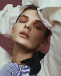 a woman wearing a white shirt and black tie with her hands on her head while she is posing for the camera