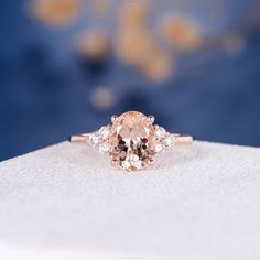 a pink diamond ring with three diamonds on it's sides, sitting on top of a white surface