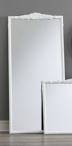 two white mirrors sitting on top of a wooden floor next to a wall mounted clock