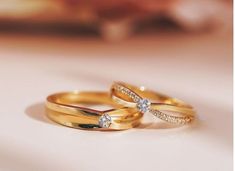 two gold wedding bands with diamonds on them