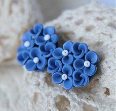 a pair of blue and white flower clip earrings on a piece of crochet