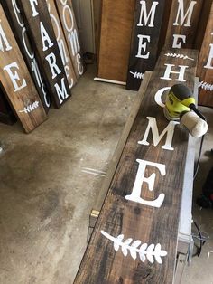 some wooden signs are sitting on the floor in front of other wood signs that say welcome home