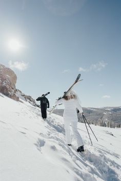 two people walking up the side of a snow covered slope