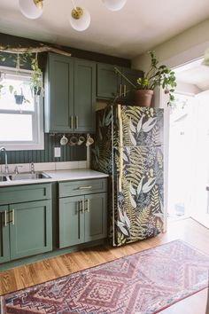 a kitchen with green cabinets and a rug on the floor