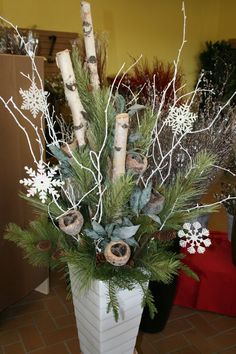 a vase filled with branches and flowers on top of a tiled floor next to a wall