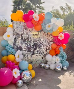 a bunch of balloons that are on the ground near a wall with flowers and butterflies