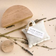 a pillow and some dried flowers on a white surface with a label that says slow north