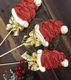 three red and white cake pops with santa hats on them sitting next to christmas decorations