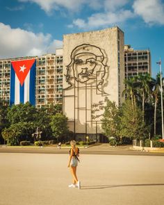 a woman standing in front of a large building with a giant mural on it's side