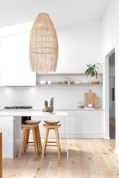 two stools are in the middle of a kitchen with white walls and wood flooring