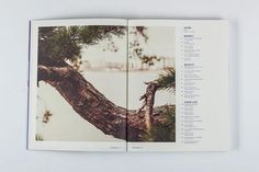 an open book with pictures of trees and water in the background on a white surface