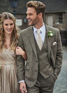 a man in a suit and tie standing next to a woman wearing a gold dress