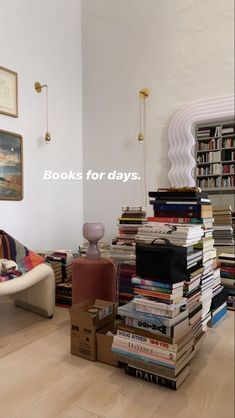 a room filled with lots of books on top of hard wood flooring next to a white wall