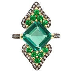 The 18 K White and Yellow Gold Ring "Green Empress” Featuring Exquisite BlueGreen Tourmaline Center, Flanked by Tsavorite Garnets and Colorless Diamonds. One of a Kind, made in NYC. BlueGreen Tourmaline 3.11 CT's Total Weight 10 Tsavorite Garnets .60 Ct's Total Weight Diamonds .40 CT's Total Weight Tsavorite Ring, Ring Tattoos, Tsavorite Garnet, Vintage Cocktail Ring, Purple Jewelry, Jewelry Wedding Rings, Colorless Diamond, Diamond Jewelry Designs, Diamond Ring Settings