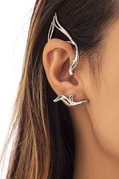 a woman wearing a pair of silver ear cuffs