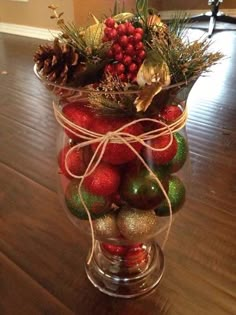 a glass vase filled with christmas ornaments on top of a wooden floor next to a door