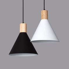 two black and white pendant lights hanging from a gray wall, one with a wooden handle