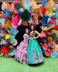 two women standing next to each other in front of colorful paper flowers and umbrellas