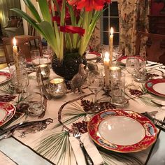 a table set with plates, silverware and candles