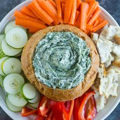 a white plate topped with carrots, cucumbers and hummus