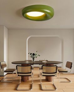 a round table with four chairs around it and a green light above the table in the middle