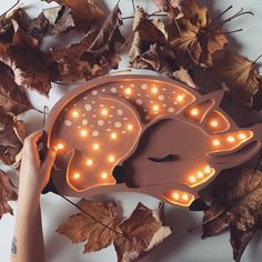 a light up hedgehog shaped clock surrounded by leaves