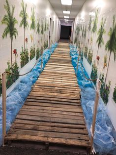 a long wooden walkway that is painted with palm trees and blue water on the sides