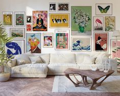 a living room filled with white furniture and lots of pictures on the wall