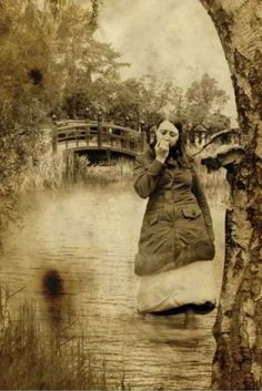 an old photo of a woman standing in the water with her hand up to her face