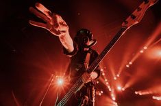 a man in a gas mask holding up his hand while standing on top of a stage