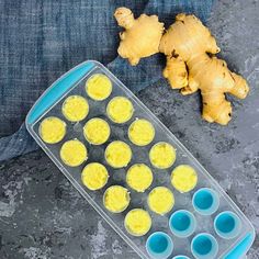 an egg tray filled with yellow eggs next to some fresh ginger on a gray surface