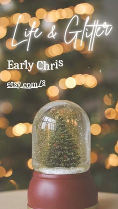 a snow globe sitting on top of a table next to a christmas tree with lights in the background