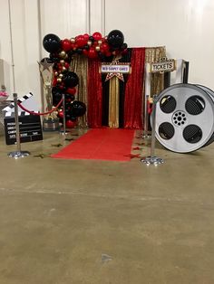 a red carpet with black and white balloons on it next to a movie reel set