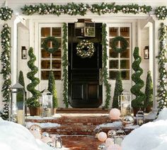 a front door decorated for christmas with wreaths and lanterns