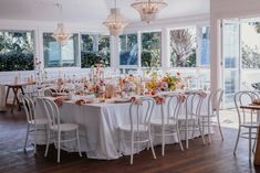 a dining room with tables and chairs set up for a formal dinner or party in front of large windows